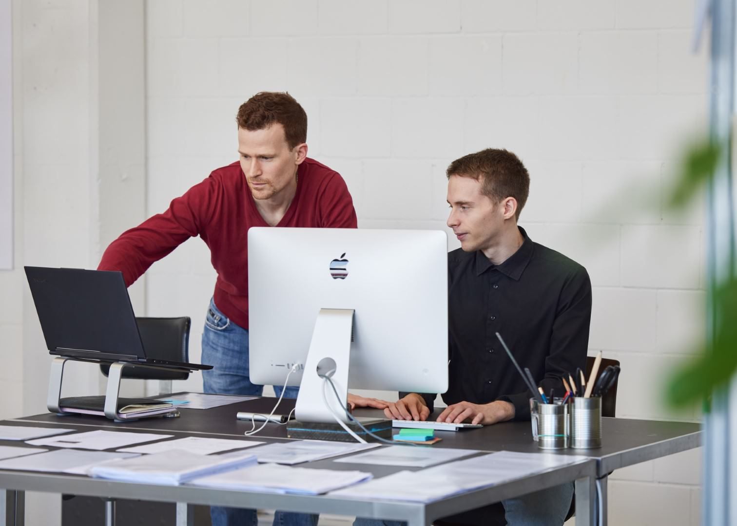 Bruno and a colleague working together at a desk with a large screen