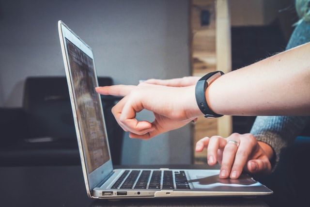 2 hands pointing at the screen of a laptop