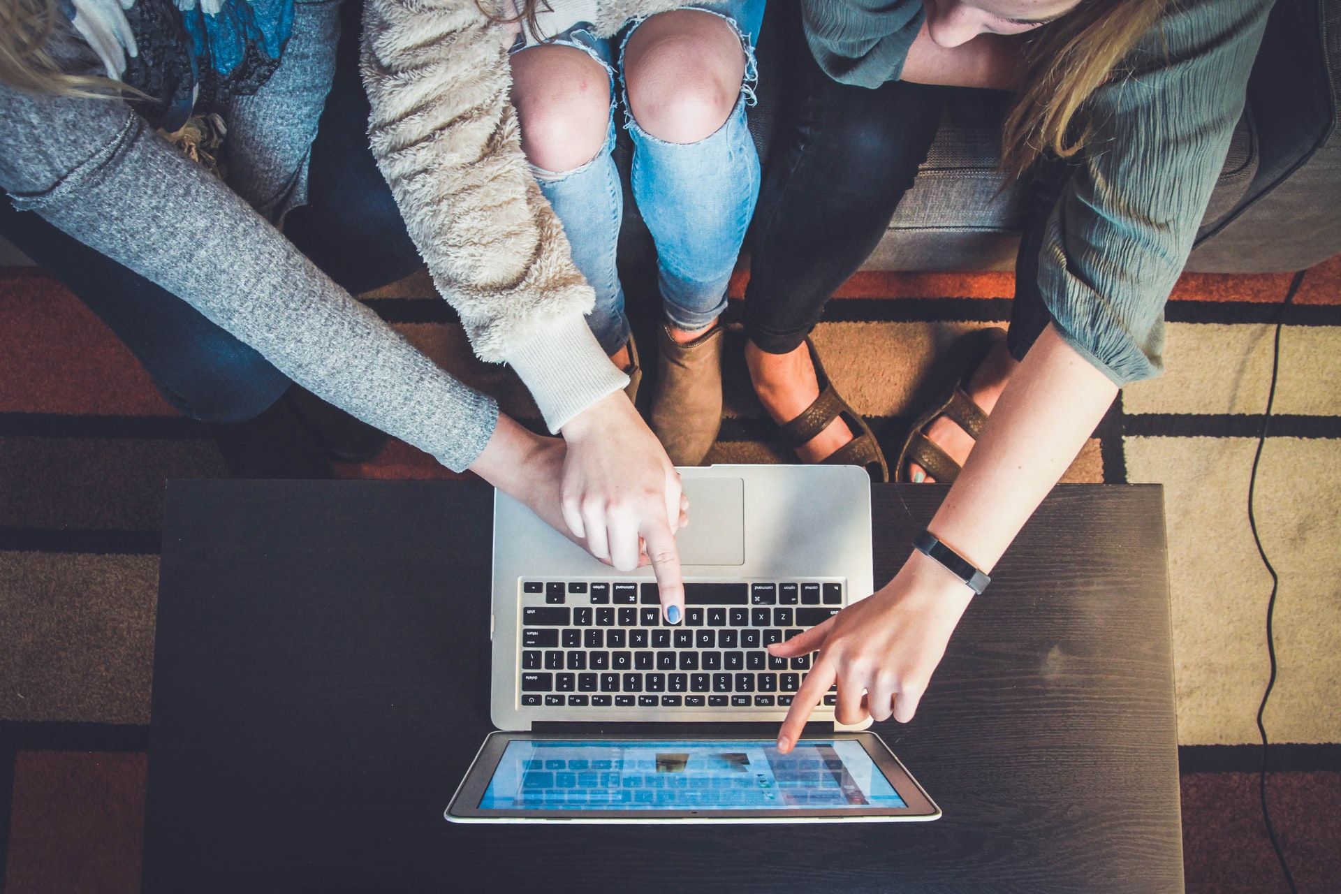 Several people pointing at a laptop together