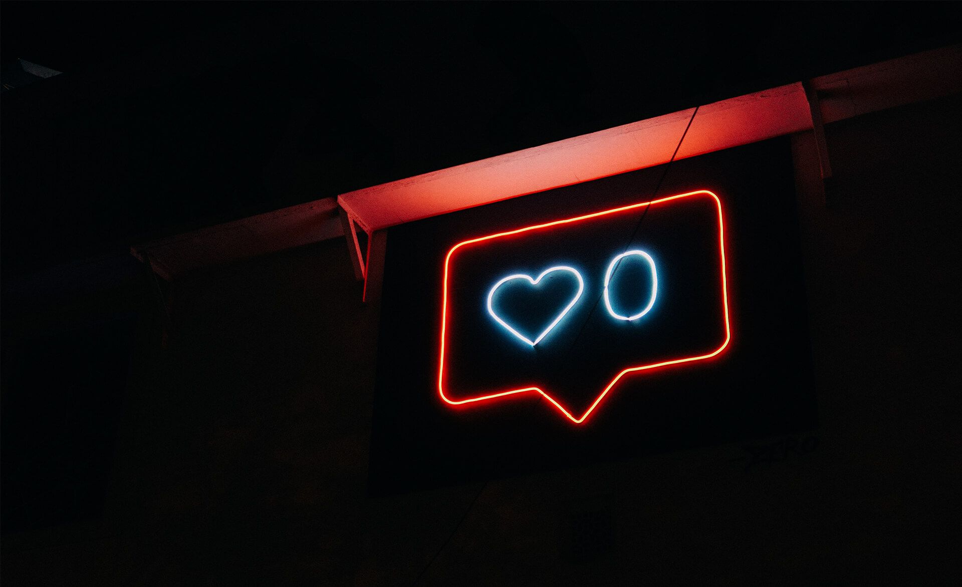 Neon sign shaped like a speech bubble with a heart and the number 0